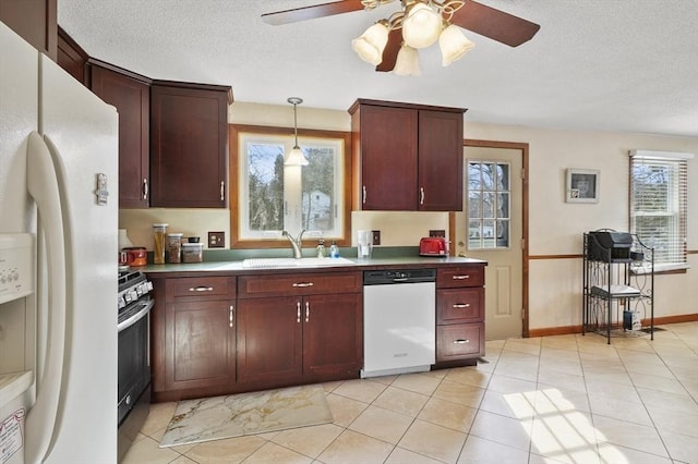 kitchen featuring white appliances, a textured ceiling, a wealth of natural light, and a sink