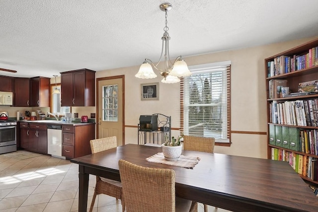 dining room with light tile patterned floors, a textured ceiling, and ceiling fan with notable chandelier