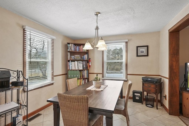 dining room with light tile patterned floors, a textured ceiling, a notable chandelier, visible vents, and baseboards