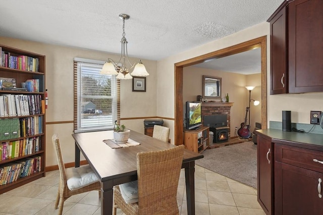 dining room featuring light tile patterned flooring, light carpet, a textured ceiling, a chandelier, and a warm lit fireplace