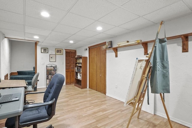 office space featuring light wood-type flooring, baseboards, a drop ceiling, and recessed lighting