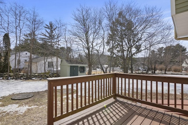 snow covered deck featuring a shed and an outdoor structure