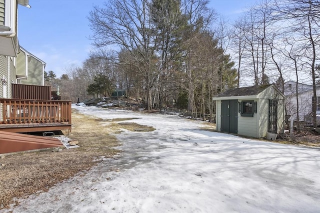 snowy yard featuring an outbuilding, a deck, and a storage unit