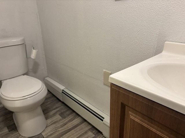 bathroom with baseboard heating, hardwood / wood-style floors, toilet, and vanity