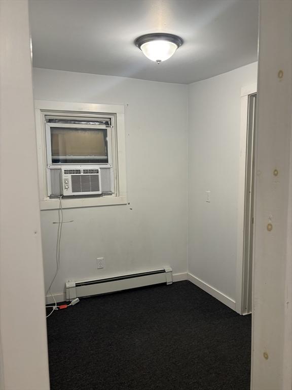 carpeted spare room with baseboard heating and cooling unit