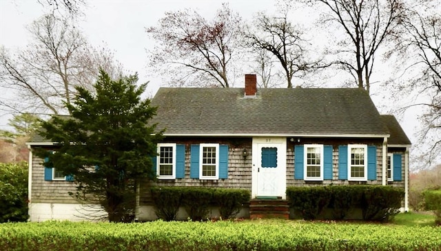 cape cod house with a chimney and a shingled roof