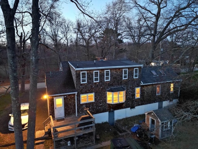 view of front facade with a chimney, a wooden deck, and roof with shingles