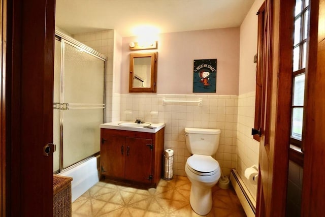 bathroom with a baseboard heating unit, tile walls, a wainscoted wall, toilet, and vanity