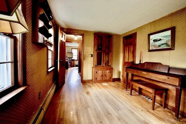 interior space featuring baseboards, wallpapered walls, wood finished floors, and plenty of natural light