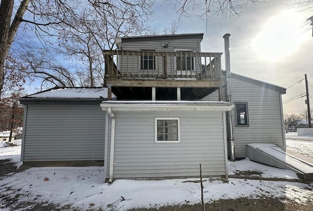 snow covered rear of property with a balcony