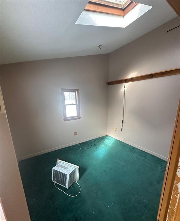 carpeted spare room with a wall mounted AC and a skylight