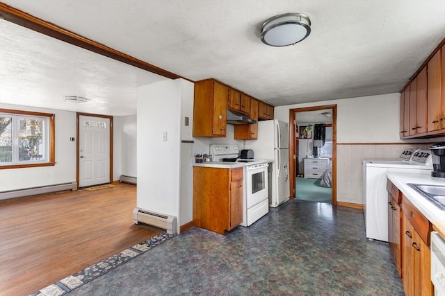 kitchen with brown cabinetry, washing machine and dryer, a baseboard heating unit, under cabinet range hood, and white appliances