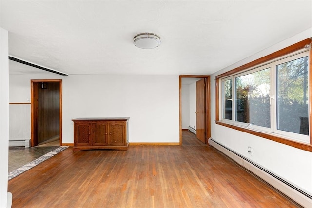 empty room with baseboards, wood finished floors, and baseboard heating