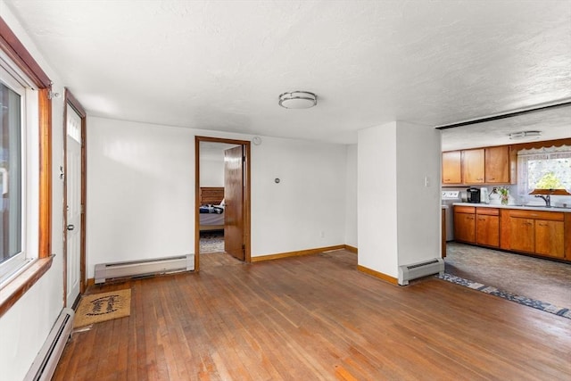 unfurnished living room with wood-type flooring, baseboards, and baseboard heating