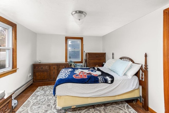 bedroom with a baseboard heating unit and wood finished floors