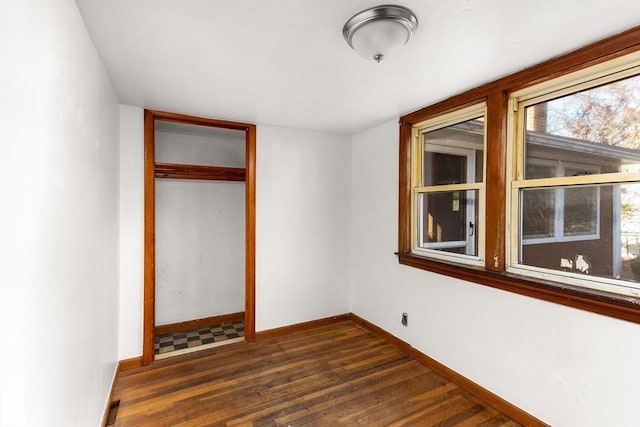 unfurnished bedroom with baseboards, dark wood finished floors, and a closet
