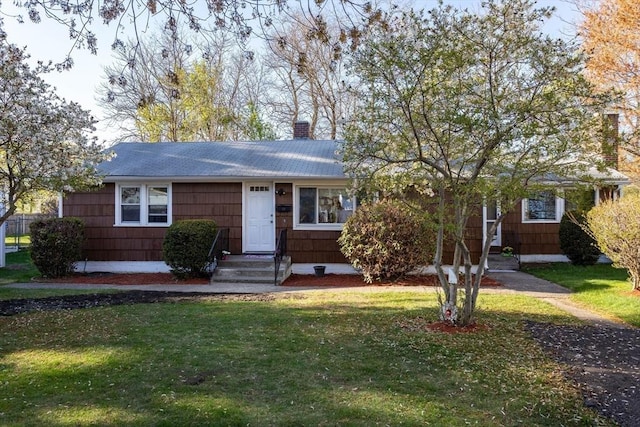 ranch-style house with a shingled roof, a front lawn, and a chimney