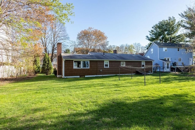 rear view of house featuring a yard and a chimney