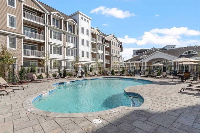 community pool with fence and a patio area