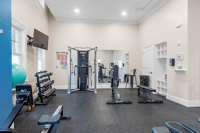 workout area with a healthy amount of sunlight, baseboards, a high ceiling, and crown molding