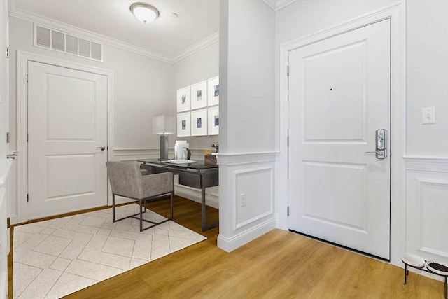 interior space featuring crown molding, light wood-type flooring, and a decorative wall