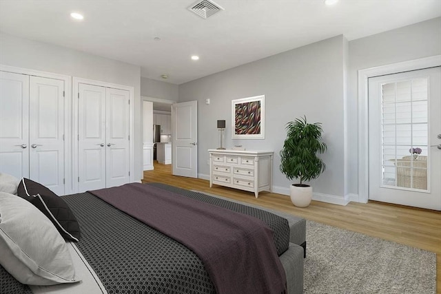 bedroom featuring visible vents, two closets, light wood-style floors, baseboards, and recessed lighting