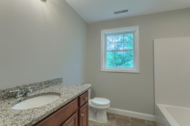 bathroom with tile patterned floors, a tub to relax in, vanity, and toilet