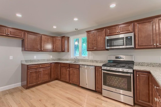 kitchen with light hardwood / wood-style floors, sink, stainless steel appliances, and hanging light fixtures