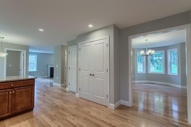 hall featuring light wood-type flooring and an inviting chandelier