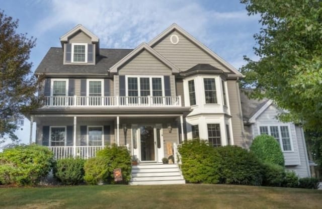 view of front of house featuring a porch, a balcony, and a front lawn