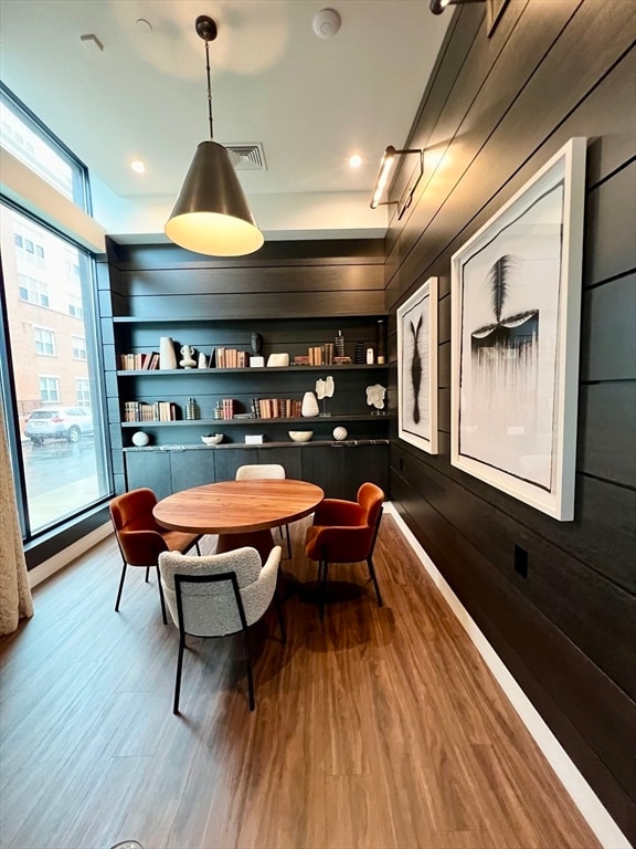 game room featuring wooden walls, plenty of natural light, built in features, and hardwood / wood-style flooring