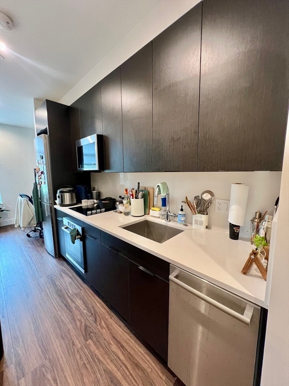 kitchen with sink, stainless steel appliances, and light hardwood / wood-style floors