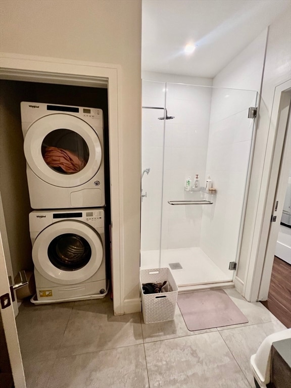 clothes washing area with stacked washer / dryer and light tile patterned floors