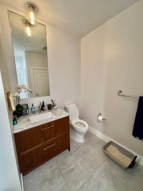 bathroom featuring tile patterned floors, vanity, a shower with shower door, and toilet