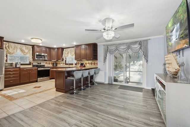 kitchen featuring a breakfast bar area, stainless steel appliances, decorative backsplash, and light hardwood / wood-style floors