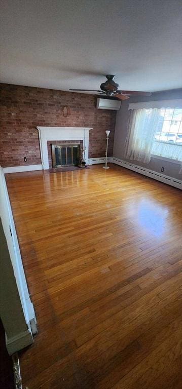 unfurnished living room with a fireplace, hardwood / wood-style floors, a wall mounted AC, and baseboard heating