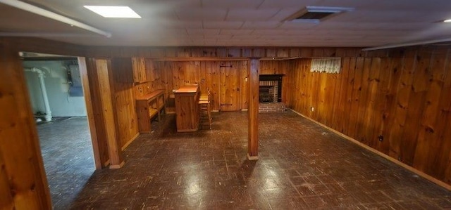 basement featuring wood walls and a brick fireplace