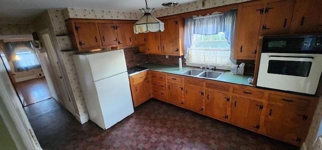 kitchen featuring pendant lighting, white appliances, and sink