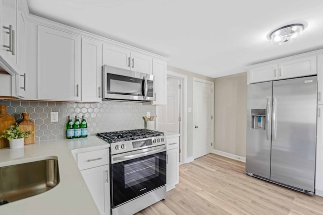 kitchen with light hardwood / wood-style flooring, stainless steel appliances, and white cabinets