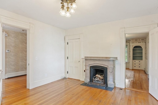 267 Pearl Hill Rd, Fitchburg, MA 01420 - unfurnished living room featuring light wood-type flooring, baseboards, a fireplace with flush hearth, and a chandelier