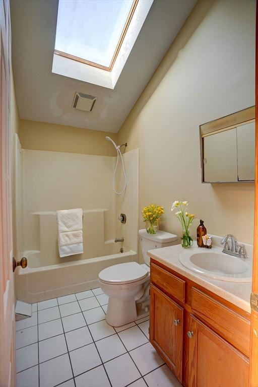 30 Royal St, Randolph, MA 02368 - full bathroom featuring a skylight, tile patterned flooring, toilet, bathtub / shower combination, and vanity
