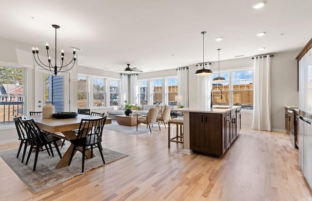 dining area featuring light wood-type flooring, ceiling fan with notable chandelier, baseboards, and recessed lighting