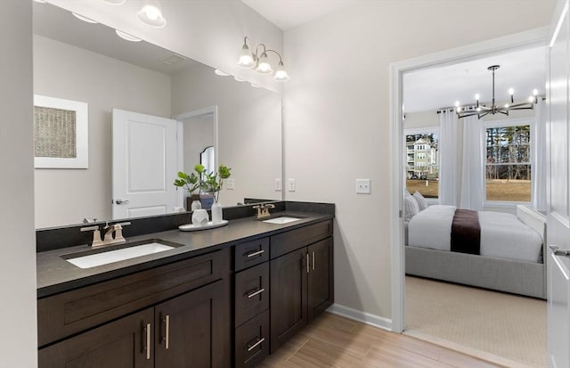 full bath featuring a sink, baseboards, double vanity, and a chandelier