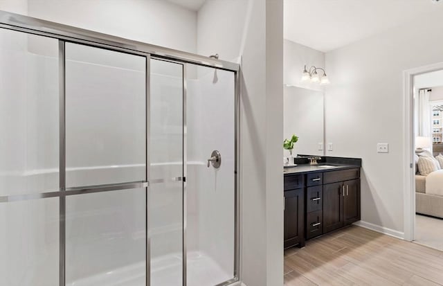 bathroom with a stall shower, wood finished floors, a sink, and ensuite bath