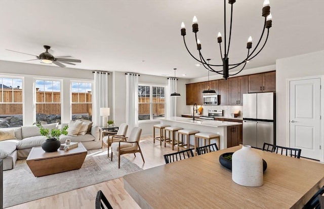 dining room featuring light wood finished floors, recessed lighting, and ceiling fan with notable chandelier