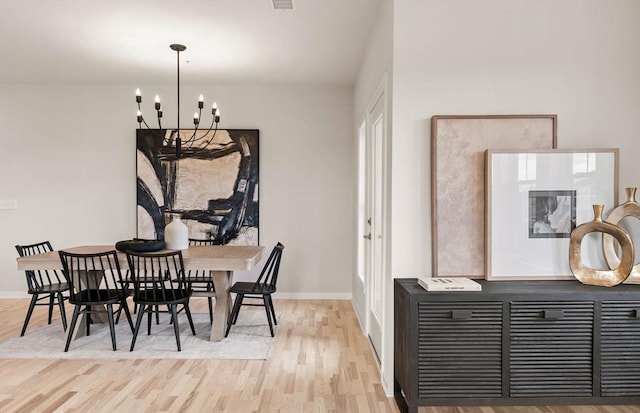 dining room featuring a chandelier, visible vents, baseboards, and wood finished floors