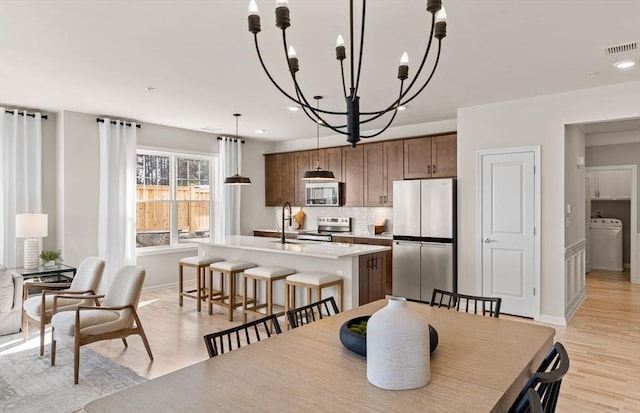 dining room featuring light wood-style flooring, visible vents, recessed lighting, washer / dryer, and a notable chandelier
