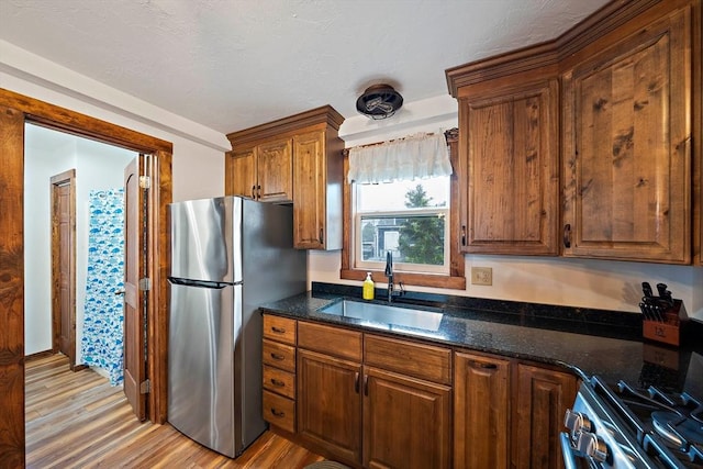 18 Marshfield Ave, Scituate, MA 02066 - kitchen featuring appliances with stainless steel finishes, a sink, light wood-style flooring, dark stone counters, and brown cabinetry