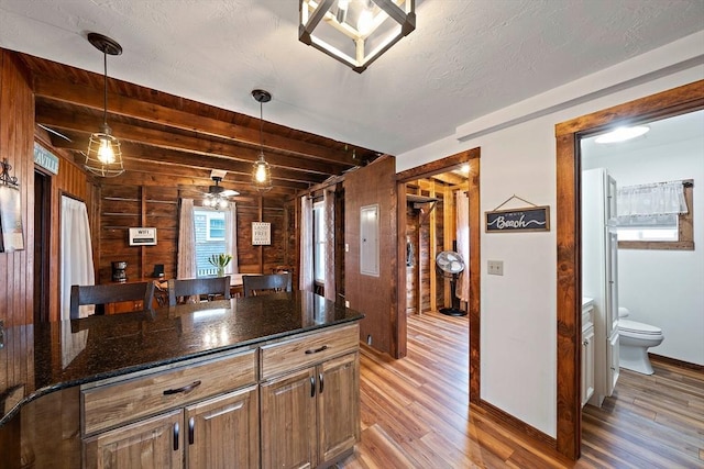 18 Marshfield Ave, Scituate, MA 02066 - kitchen with light wood-type flooring, wood walls, beamed ceiling, dark stone counters, and baseboards