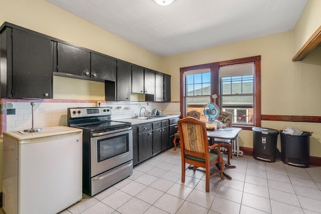 kitchen with light tile patterned floors, tasteful backsplash, stainless steel electric range, and sink